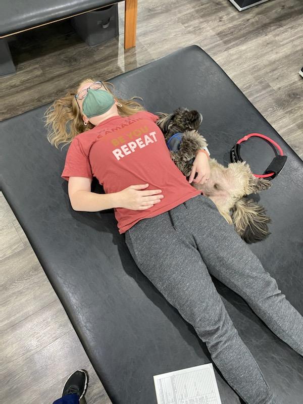 Patient lying on therapy table with dog nearby